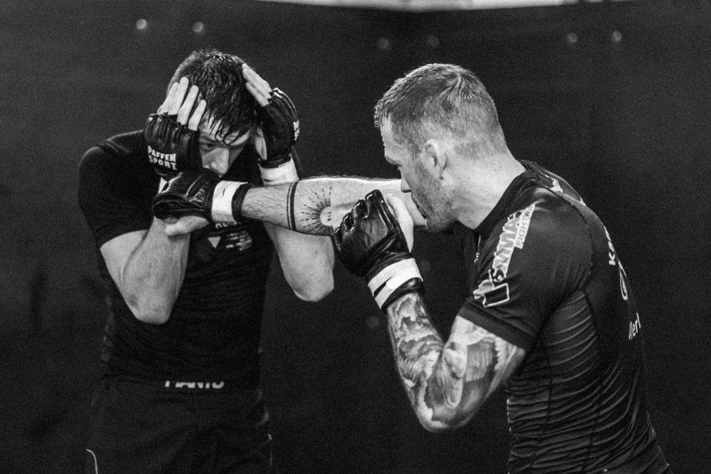 MMA-Sparring mit Schlag zum Kopf, der geblockt wird